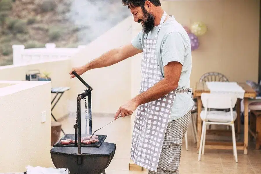 Man smiling and grilling outside